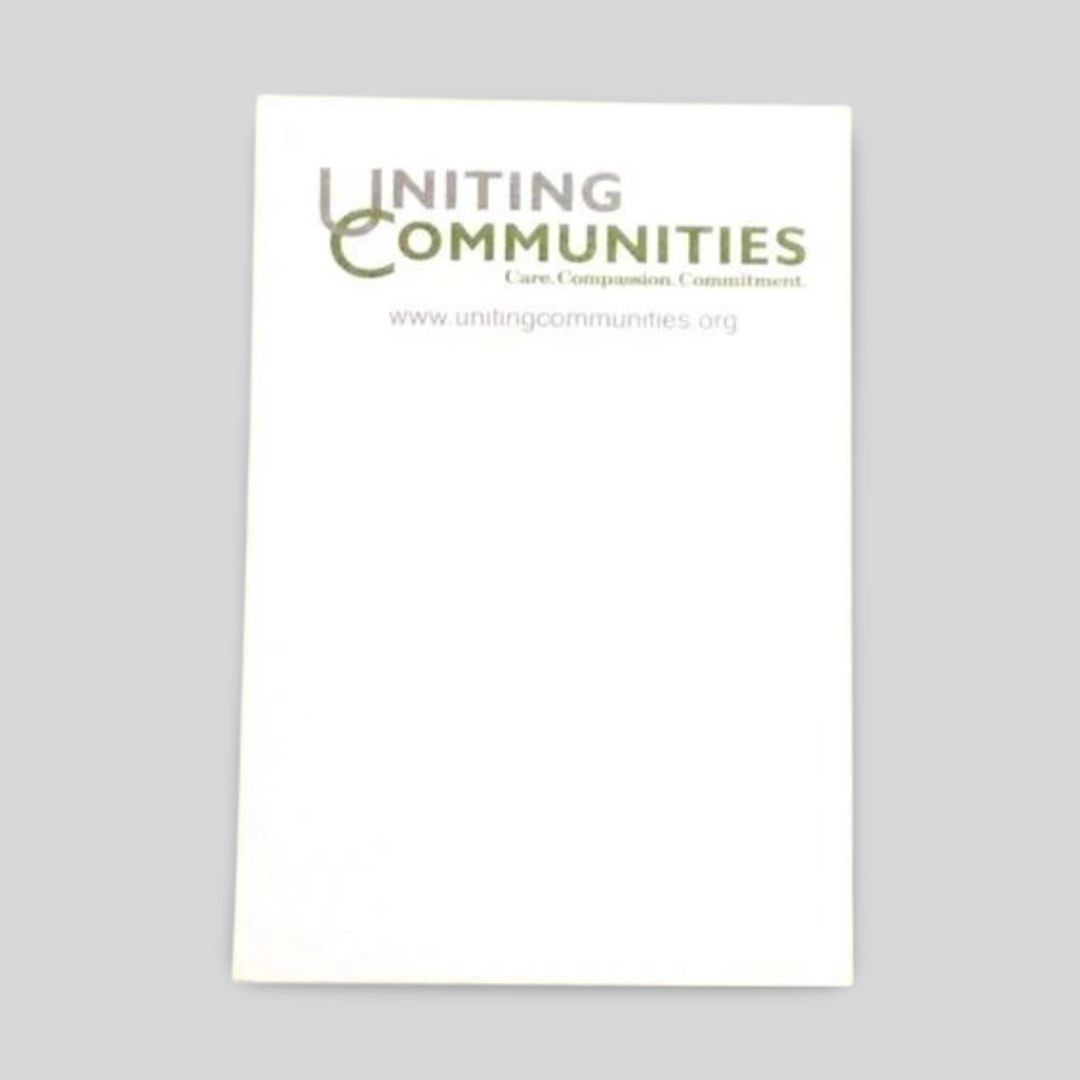 A rectangular notepad featuring the Uniting Communities logo at the top, along with the tagline "Care. Compassion. Commitment." and the website www.unitingcommunities.org. The design is clean and professional, with ample space for notes, making it ideal for organisational and community-focused use.