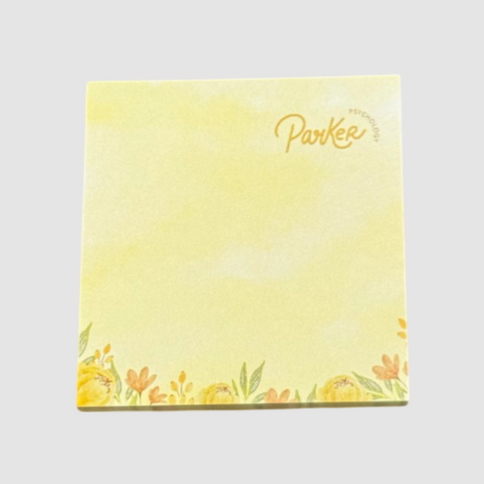 This notepad features a cheerful yellow design with a floral border at the bottom, adding a touch of elegance and charm. The "Parker Psychology" logo is printed subtly in the top right corner, making it a personalised stationery option for professional use. Ideal for therapy offices, events, or promotional purposes, it combines functionality with an uplifting aesthetic.