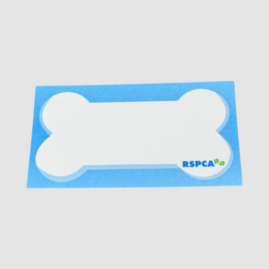 This image showcases a dog-bone-shaped notepad featuring the RSPCA logo at the bottom right. The notepad is set against a blue rectangular backing, creating a playful and pet-themed design. This product is ideal for promoting animal welfare organisations, pet-related businesses, or events, while providing a functional and visually appealing stationery item.